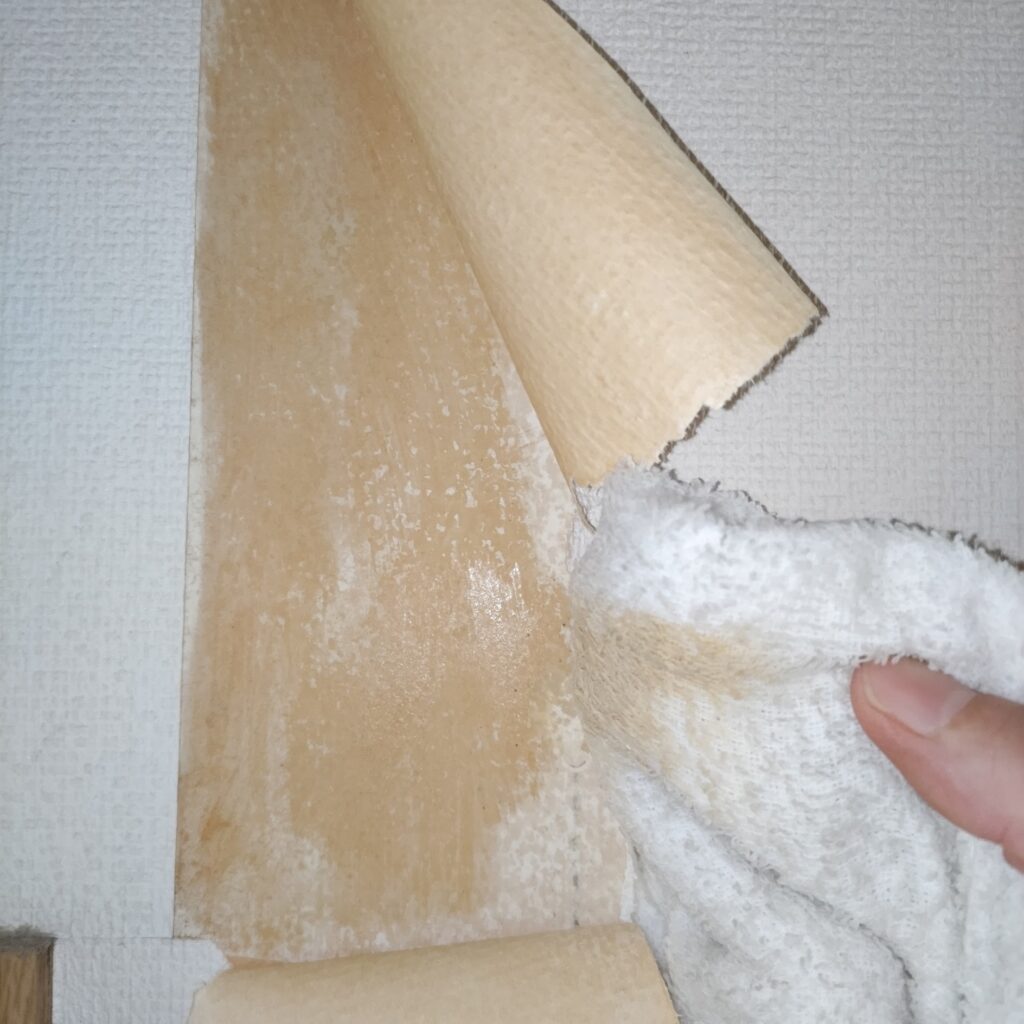 めくれた壁紙の裏を掃除している様子