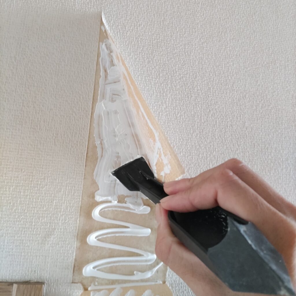 壁紙の裏に塗ったジョイントコークをヘラで伸ばしている様子